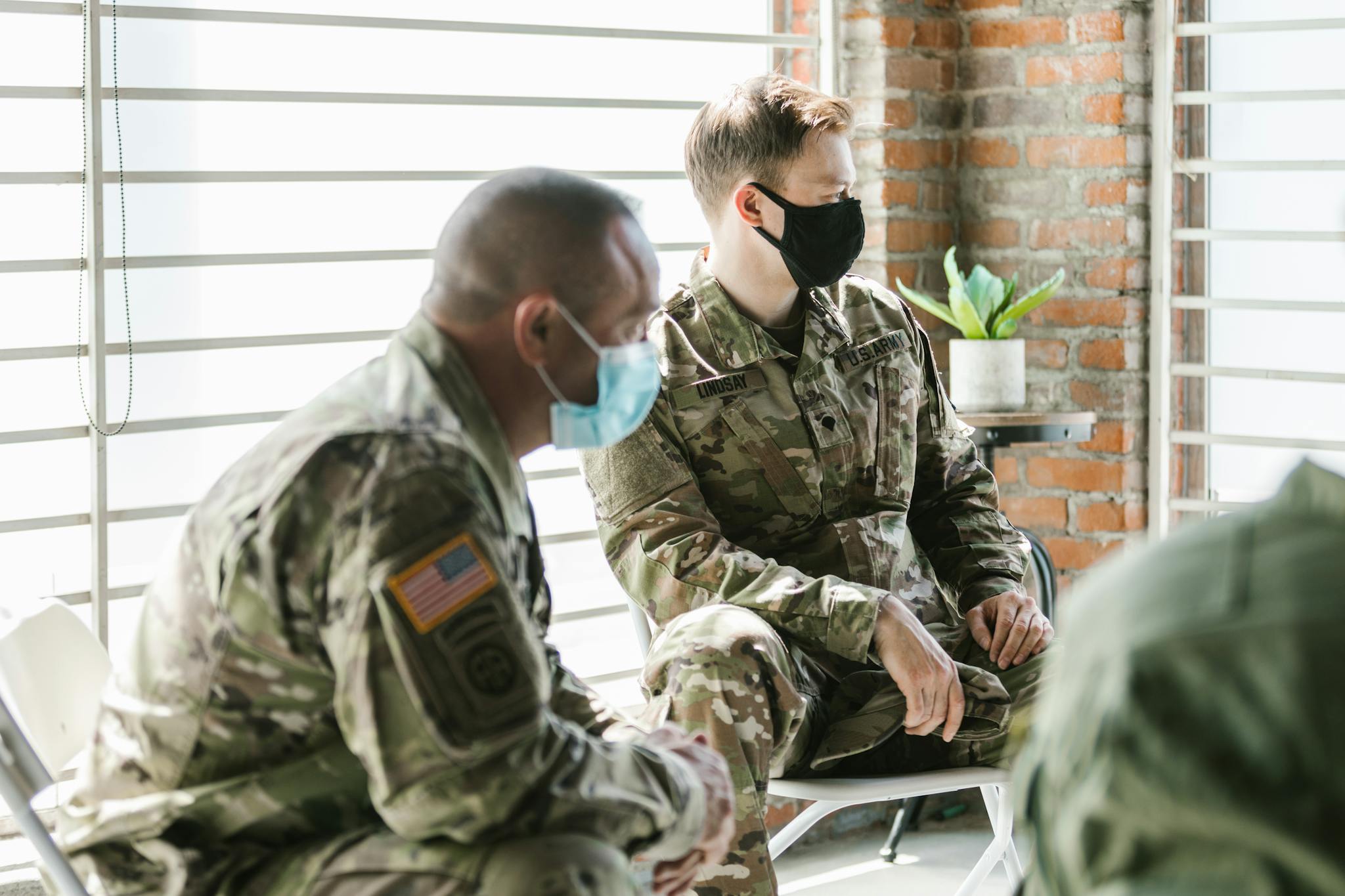 A group therapy session with military personnel wearing masks indoors.